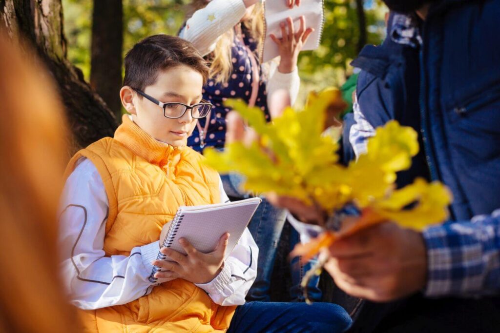 chlapec si zapisuje informácie o jesenných listoch do zošita
