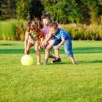 deti na zelenom trávniku behajú za loptou