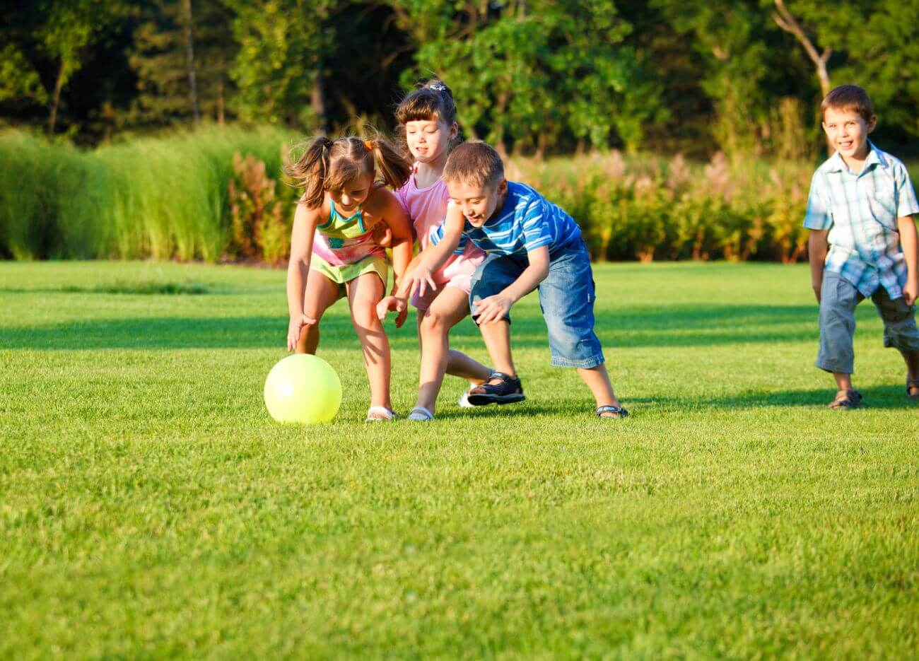 deti na zelenom trávniku behajú za loptou