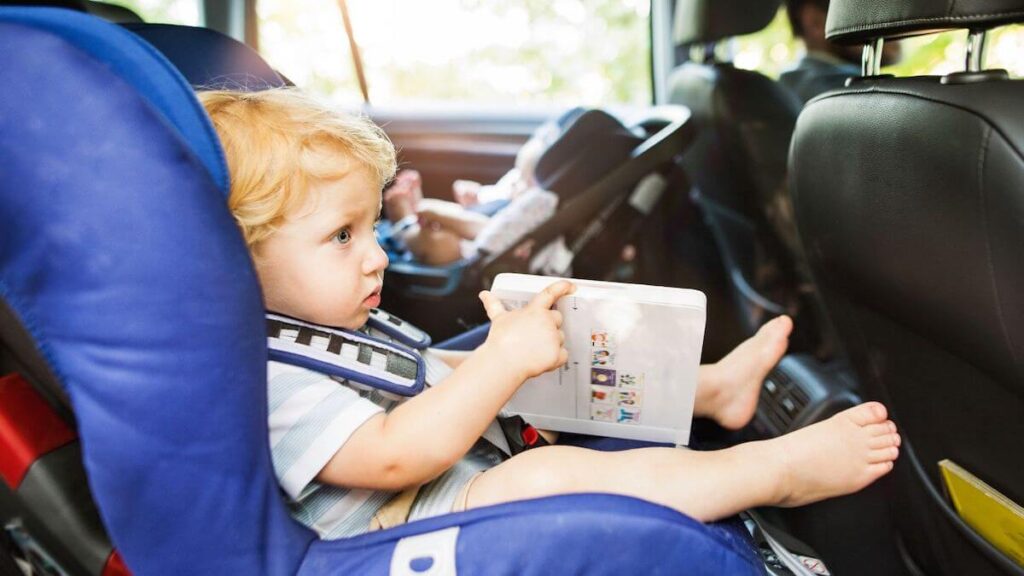 dieťa v autosedačke drží leporelo
